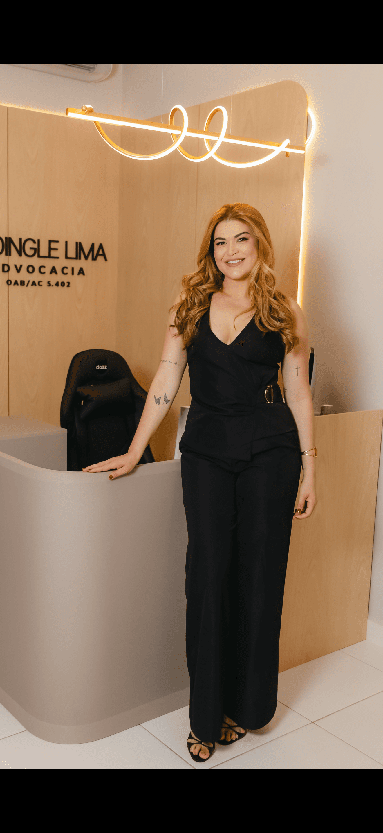Jhoingle Lima em pé na recepção do escritório